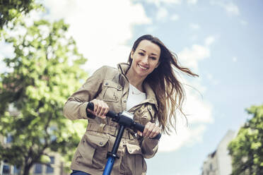 Porträt einer lächelnden Frau mit E-Scooter - BFRF02034