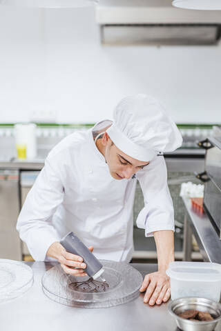 Jungkoch bereitet einen Dessertteller vor, lizenzfreies Stockfoto