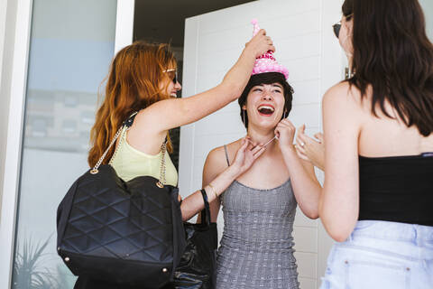 Freundinnen feiern Geburtstag, Freunde überraschen das Geburtstagskind an der Tür, lizenzfreies Stockfoto