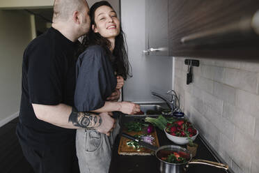 Mann umarmt und küsst Frau in der Küche - EYAF00265