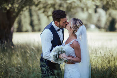 Romantic bride and groom kissing in woodland - ISF21933