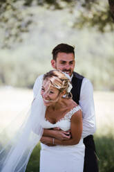 Romantic groom hugging bride from behind in woodland - ISF21934