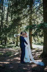 Romantic groom lifting up bride to kiss in woodland - ISF21941