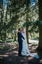 Romantischer Bräutigam hebt die Braut zum Kuss im Wald hoch - ISF21941