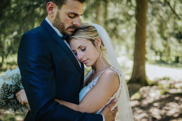 Romantic bride and groom hugging each other in woodland - ISF21942