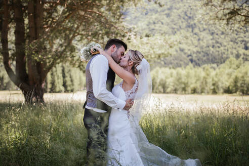 Romantisches Paar am Hochzeitstag, das sich im Wald küsst, Stresa, Piemonte, Italien - ISF21945