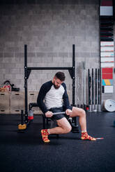 Junger Mann massiert Oberschenkel mit Muskelroller im Fitnessstudio - ISF21992