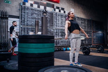 Young woman lifting weight bar in gym - ISF22005