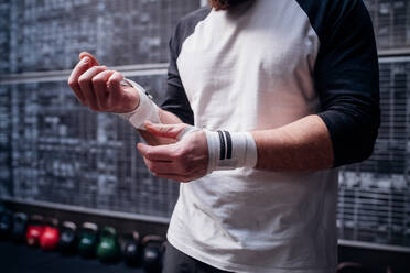 Mann beim Anlegen von Handschuhen im Fitnessstudio - ISF22007