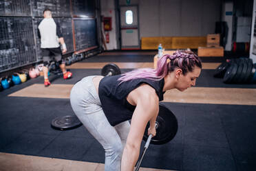 Junge Frau hebt Langhantel im Fitnessstudio - ISF22010