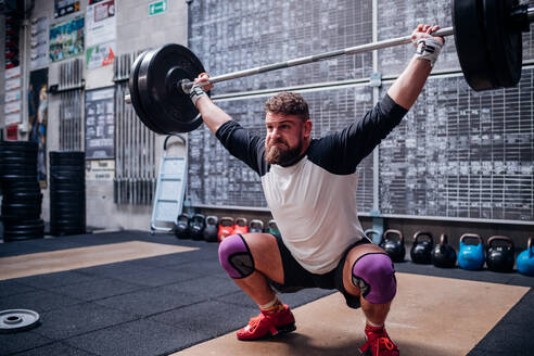 Young man lifting barbell in gym - ISF22020