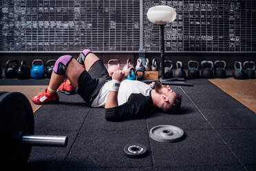 Exhausted young man taking break in gym - ISF22028