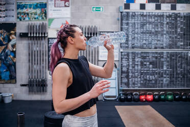 Junge Frau trinkt Wasser im Fitnessstudio - ISF22030