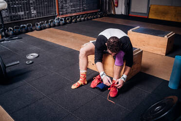 Man tying shoelace in gym - ISF22032