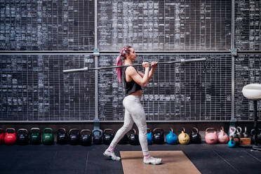 Young woman lifting weight bar in gym - ISF22047