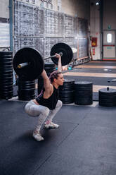 Young woman lifting barbell in gym - ISF22050