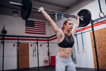 Young woman lifting barbell in gym - ISF22059