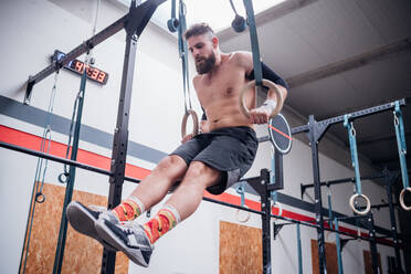 Junger Mann balanciert auf Gymnastikringen in der Turnhalle - ISF22067