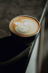 Frische Tasse Milchkaffee mit Blattmuster auf dem Rand der Kaffeetheke, Nahaufnahme - ISF22082