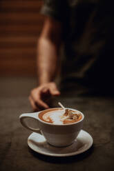 Barista at cafe counter with cup of mocha topped with toasted marshmallow, cropped shallow focus - ISF22102