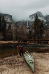 Young female canoeist looking out from riverbank, rear view, Yosemite Village, California, USA - ISF22103
