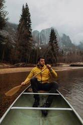 Young male canoeist rowing canoe on river, Yosemite Village, California, USA - ISF22106