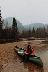 Junge Kanufahrerin sitzt auf einem Kanu im Fluss, Yosemite Village, Kalifornien, USA - ISF22109