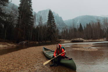 Glückliche junge Kanufahrerin, die auf einem Kanu im Fluss sitzt, Yosemite Village, Kalifornien, USA - ISF22111