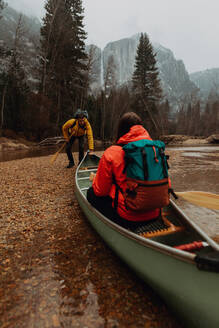 Junges Kanufahrerpaar, das sich vom Flussufer abstößt, Yosemite Village, Kalifornien, USA - ISF22112
