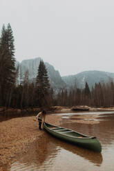 Junge Kanufahrerin beim Ziehen des Kanus aus dem Fluss, Yosemite Village, Kalifornien, USA - ISF22114