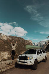Junge Frau auf einer Mauer am Straßenrand mit erhobenen Händen, Rückansicht, Yosemite Village, Kalifornien, USA - ISF22120