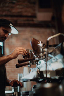 Barista bei der Bedienung einer Kaffeemaschine in einem Café, Seitenansicht mit flachem Fokus - ISF22124