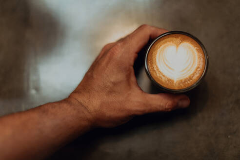 Barista platziert Tasse Latte mit Herzform auf Café-Theke, Overhead Nahaufnahme der Hand - ISF22128