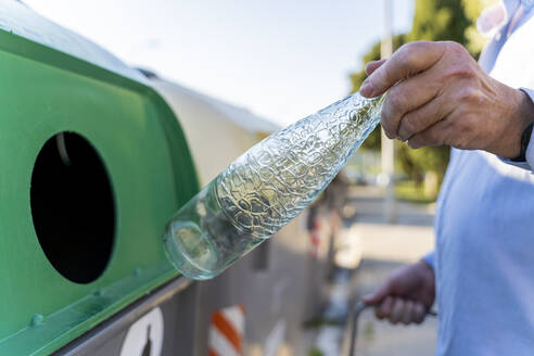 Close-up of man putting bottle into bottle bank - AFVF03456