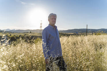 Portrait of senior man standing on a field at sunset - AFVF03465