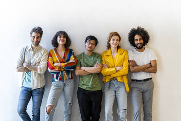 Portrait of confident group of friends standing at a wall - AFVF03520