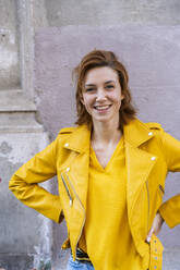 Portrait of a smiling young woman wearing a yellow jacket - AFVF03541
