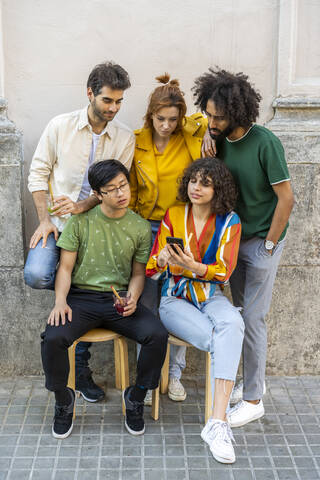 Friends sharing cell phone in the city stock photo