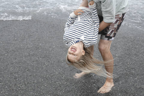 Vater spielt mit seiner Tochter am Strand, lizenzfreies Stockfoto