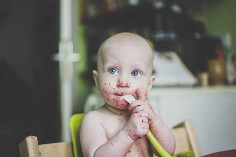 Baby boy making mess while eating stock photo