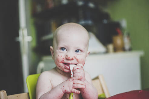 Lächelnder kleiner Junge, der beim Essen Unordnung macht - IHF00155