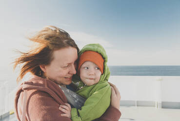 Mother carrying baby boy in a sling on a ferry - IHF00158