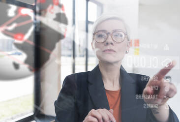 Businesswoman touching glass wall with data in office - UUF17906