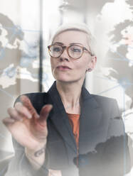 Businesswoman touching virtual glass wall in office - UUF17909