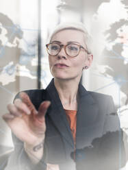 Geschäftsfrau berührt virtuelle Glaswand im Büro - UUF17909
