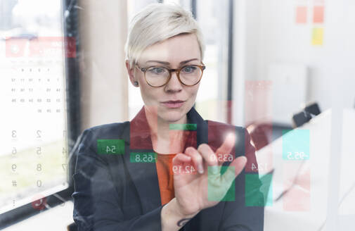 Geschäftsfrau berührt Glaswand mit Daten im Büro - UUF17910
