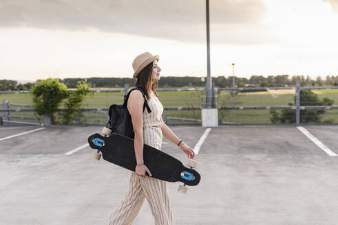 Junge Frau mit Longboard auf dem Parkdeck - UUF17947