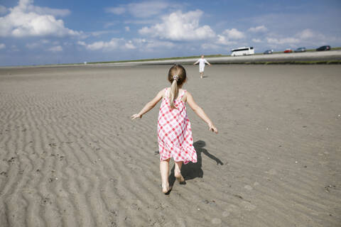 Rückenansicht eines kleinen Mädchens, das am Strand läuft, Bergen op Zoom, Niederlande, lizenzfreies Stockfoto