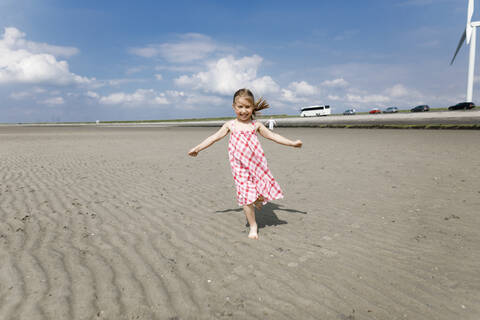 Glückliches kleines Mädchen, das am Strand läuft, Bergen op Zoom, Niederlande, lizenzfreies Stockfoto