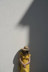 Weiblicher Tourist mit Hut, der in der Stadt an einer Mauer steht - AHSF00574